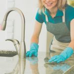 Woman Cleaning Kitchen Counter with Gloves and Sponge