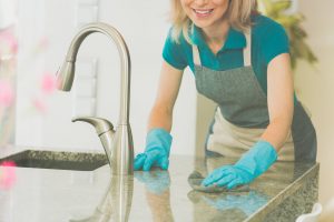 Woman Cleaning Kitchen Counter with Gloves and Sponge